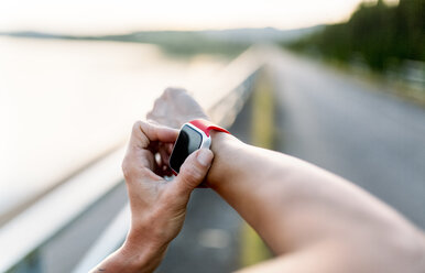 Woman adjustung settings of smart watch for outdoor training - MGOF002041