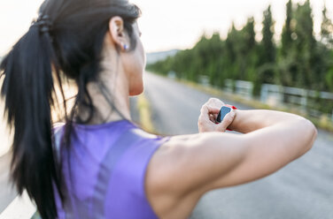 Frau passt die Einstellungen ihrer Smartwatch für das Training im Freien an - MGOF002042