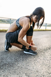 Woman tying laces of sports shoes - MGOF002051