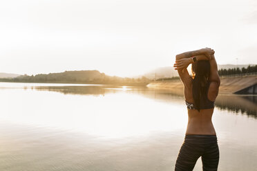 Female athlete stretching at the sea at sunset - MGOF002064