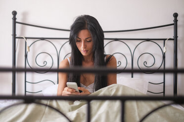 Woman sitting in bed, smartphone - SIPF000672