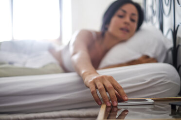 Young woman in bed, taking smartphone - SIPF000675