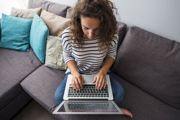 Frau sitzt auf der Couch und benutzt einen Laptop - SIPF000691