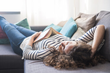 Woman with book relaxing on couch - SIPF000694