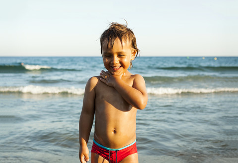 Glücklicher kleiner Junge vor dem Meer stehend, lizenzfreies Stockfoto