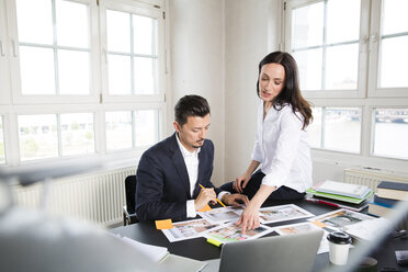 Geschäftsmann und Frau sitzen am Schreibtisch im Büro und arbeiten zusammen - FKF001954