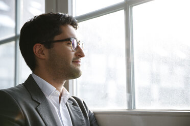 Businessman standing at the window with arms crossed - FKF001986