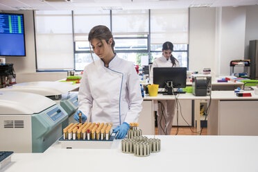 Laboratory technician in analytical laboratory taking test tubes fron´m a centrifuge container - ABZF000843