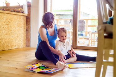 Pregnant mother looking at picture book with her little son - HAPF000600