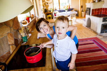 Kleiner Junge hilft seiner schwangeren Mutter beim Kochen, rührt im Topf - HAPF000606