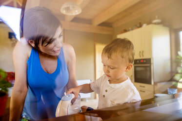Kleiner Junge hilft seiner schwangeren Mutter in der Küche mit einem elektrischen Schnurrbart - HAPF000612