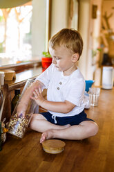 Little boy is playing in kitchen, nibbling food - HAPF000614