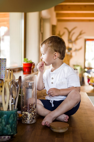 Kleiner Junge spielt in der Küche, knabbert Essen, lizenzfreies Stockfoto