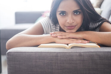 Portrait of teenage girl lying on the couch with a book - SIPF000730