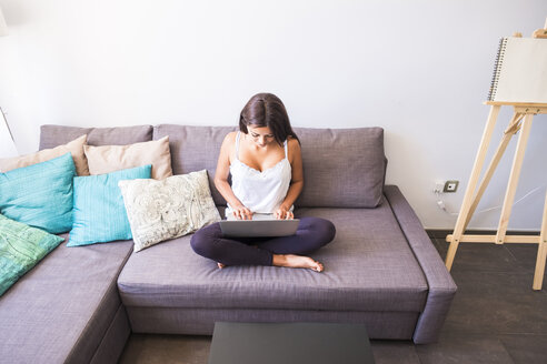 Teenager-Mädchen sitzt auf der Couch und benutzt einen Laptop - SIPF000736