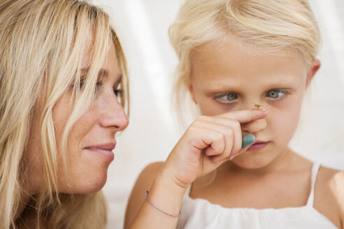 Cross-eyed little girl watching fly sitting on her finger - TCF005020