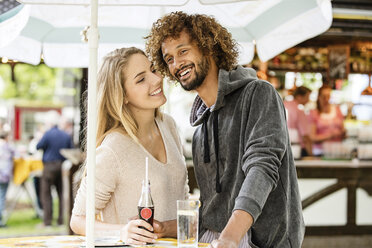 Young couple drinking beverage at a fun fair food stand - GD001068