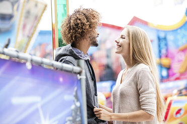 Happy couple on a carousel at a fun fair - GD001073