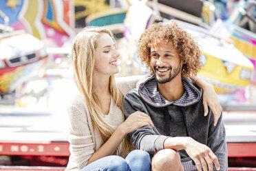 Happy couple on a carousel at a fun fair - GD001074