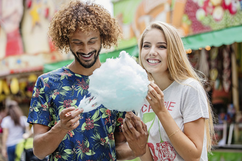 Junges Paar isst Zuckerwatte auf einem Jahrmarkt, lizenzfreies Stockfoto