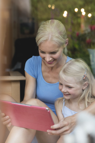 Mutter und kleine Tochter schauen gemeinsam auf ein Tablet, lizenzfreies Stockfoto