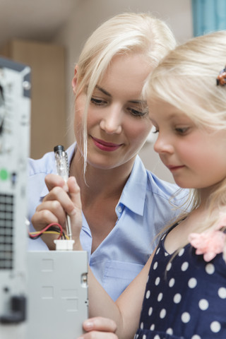 Mutter und kleine Tochter überprüfen den Stromfluss eines Computers, lizenzfreies Stockfoto