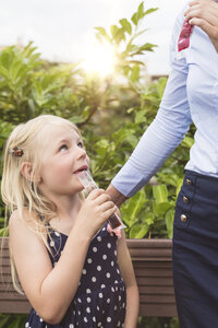 Kleines Mädchen isst Wassereis und sieht ihre Mutter an - MIDF000781