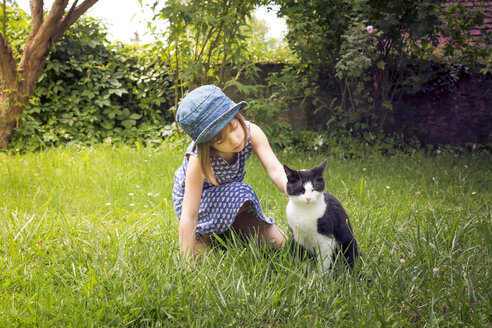 Little girl stroking cat on a meadow - LVF005140