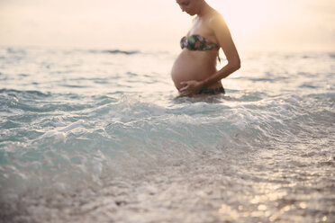 Pregnant woman standing in the sea at backlight - MBEF001425