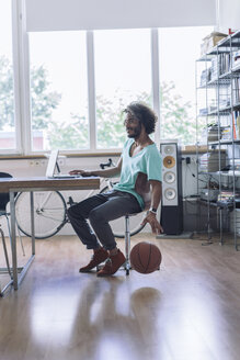 Junger Mann spielt mit Basketball im Büro - RIBF000471
