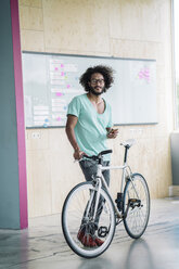 Junger Mann mit Fahrrad und Smartphone - RIBF000478