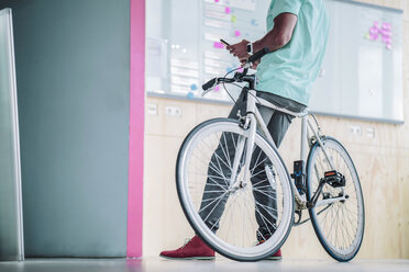 Junger Mann mit Fahrrad und Smartphone - RIBF000482