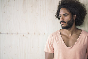 Young man leaning against wooden wall, looking away - RIBF000491