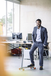 Young businessman with kickboard in office - RIBF000506