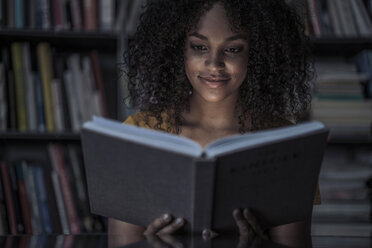 Junge Frau liest ein Buch in der Bibliothek - RIBF000507