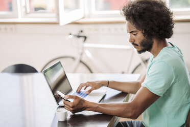 Junger Mann im Büro mit Laptop - RIBF000524