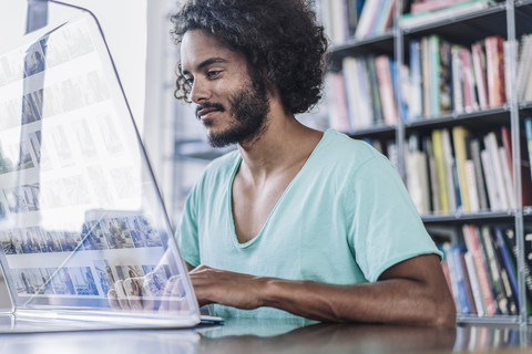 Young man working in library, using futuristic computer stock photo