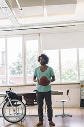 Young man playing with basketball in office - RIBF000541