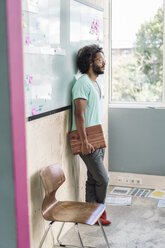 Young creative proffessional leaning against white board in office - RIBF000549