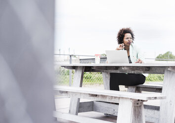 Nachdenkliche Geschäftsfrau bei der Arbeit im Freien mit ihrem Laptop - UUF008174