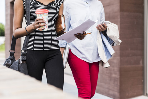 Two businesswomen walking side by side, partial view stock photo