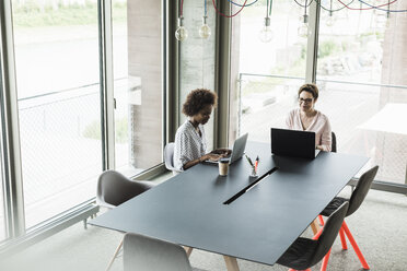 Two women working at laptops in an office - UUF008214