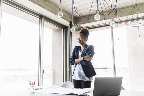 Smiling businesswoman with arms crossed standing in office stock photo