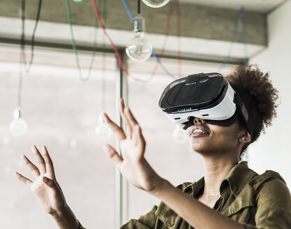 Woman in office using virtual reality glasses - UUF008264