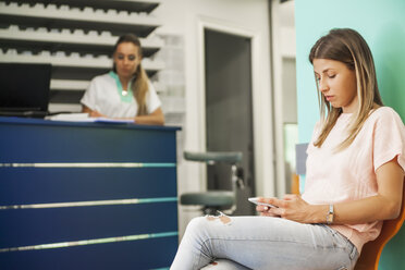 Patient mit Smartphone im Wartezimmer des Zahnarztes - ZEDF000238