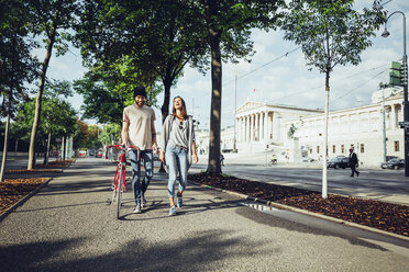 Austria, Vienna, young couple with bicycle in front of Parliament building - AIF000344