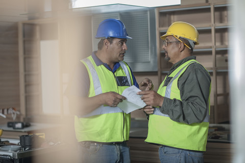 Zwei Bauarbeiter im Gespräch, lizenzfreies Stockfoto