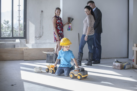 Junge mit Schutzhelm spielt auf einer Baustelle, lizenzfreies Stockfoto