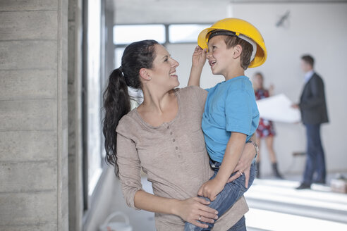 Mutter und Sohn mit Schutzhelm auf einer Baustelle - ZEF009195