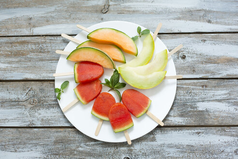 Plate of homemade watermelon ice lollies, slices of Galia and Cantaloupe melon - MAEF011914